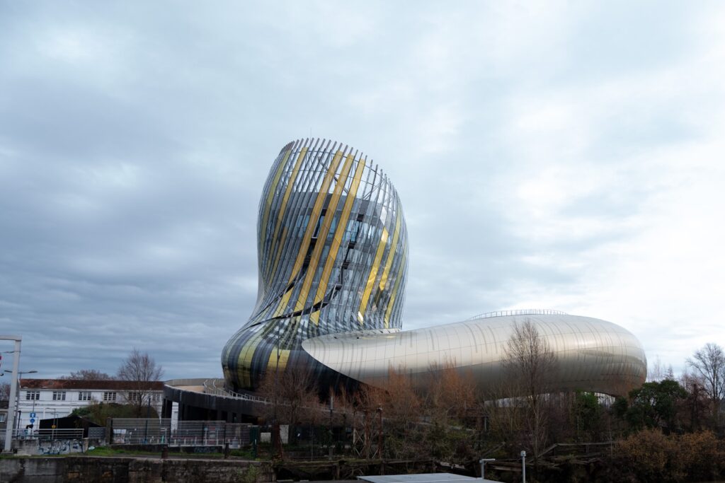 a large building with a curved metal structure next to a body of water